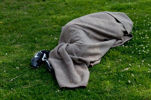 Persona sin hogar sobre la hierba - © Norbert Pousseur