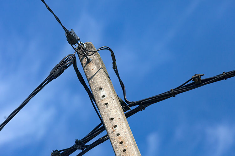 Vieux poteau électrque portant des fils gaînés de noir -  © Norbert Pousseur